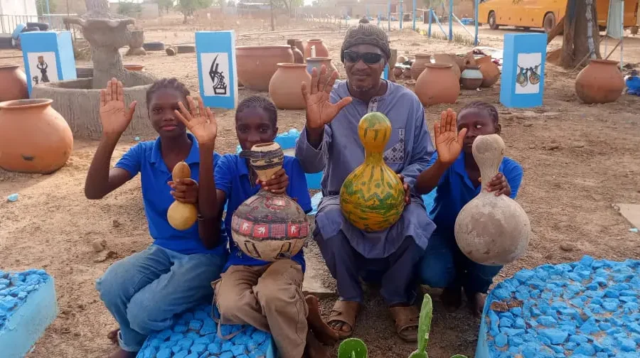Des élèves présentent des calebasses décorées avec un animateur.